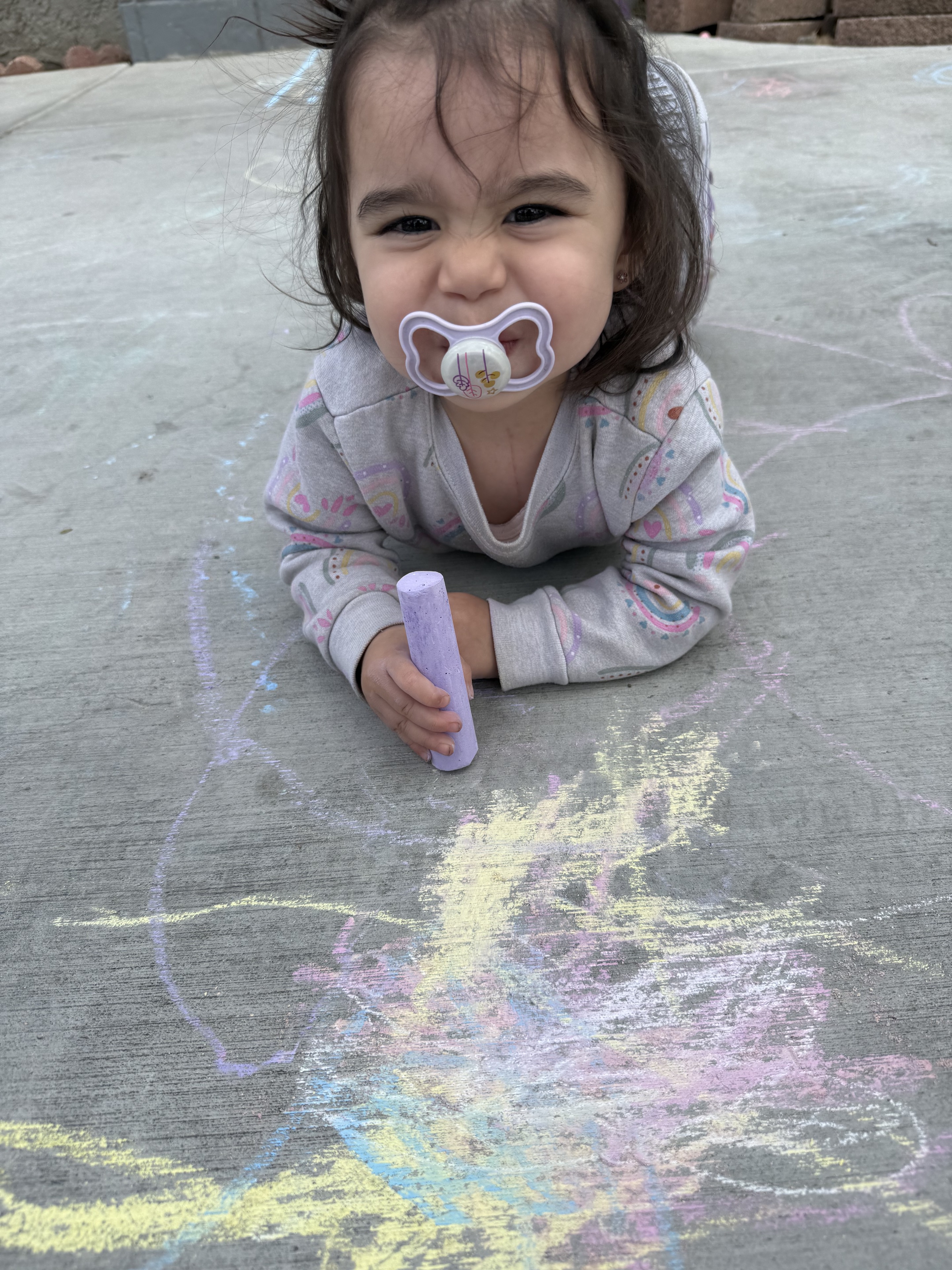 A young child enjoying colorful sidewalk chalk during outdoor play